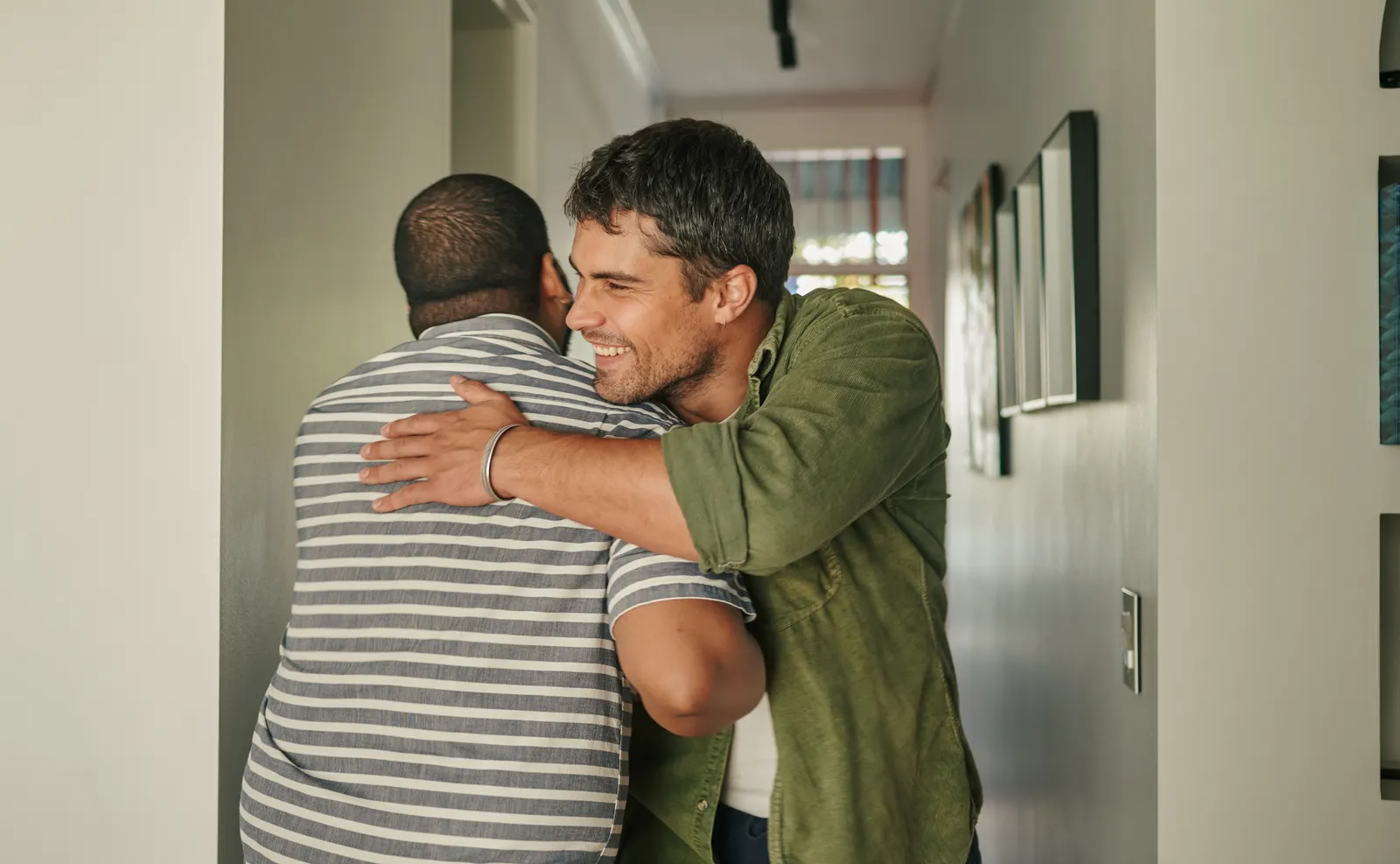 Imagem de dois homens se cumprimentando em inglês em um corredor com quadros pendurados.