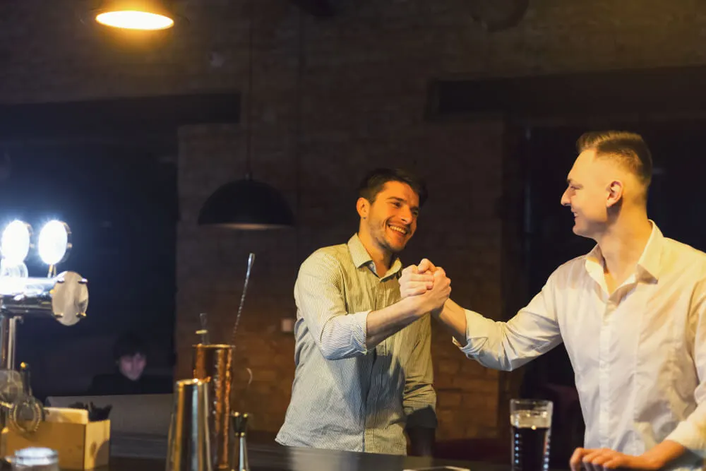 Dois amigos se cumprimentando com um aperto de mãos informal